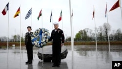 (FILE) Two military personnel stand underneath the flags of NATO alliance members during wreath laying ceremony at NATO headquarters in Brussels, Thursday, April 4, 2024.