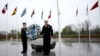 Dos militares se ven bajo las banderas de los estados miembros de la OTAN durante una ofrenda floral en la sede de la alianza en Bruselas, el jueves 4 de abril de 2024. La OTAN celebra el jueves 75 años desde la firma de su tratado fundacional.