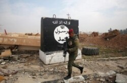 FILE - An Iraqi soldier walks next to a wall painted with the black flag commonly used by Islamic State militants, north of Mosul, Iraq, Jan. 21, 2017.