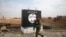 FILE - An Iraqi soldier walks next to a wall painted with the black flag commonly used by Islamic State militants, north of Mosul, Iraq, Jan. 21, 2017.