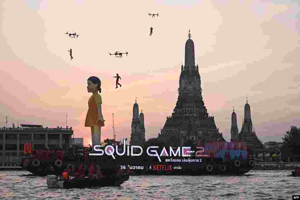 A 12-meter-tall statue of Young-hee, the iconic doll from Netflix&#39;s South Korean TV series Squid Game&nbsp;is seen on a barge in front of Wat Arun temple on the Chao Prayer River ahead of the launch of Season 2, in Bangkok, Thailand. (Photo by Lillian SUWANRUMPHA / AFP)