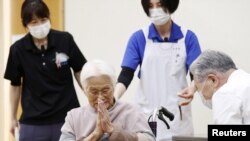 An elderly woman gestures to express gratitude after receiving a coronavirus disease (COVID-19) vaccination in Itami, western Japan, Apr. 12, 2021, in this photo released by Kyodo. (Kyodo/via Reuters)