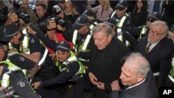 Kardinal George Pell (baju hitam/tengah), dikelilingi oleh para Polisi ketika tiba di pengadilan kota Melbourne, Australia, hari Rabu (26/7). 