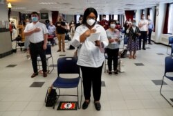 FILE - Ifeoma Eh, a citizen candidate from Nigeria, stands with others socially distanced and wearing protective face masks, during a U.S. Citizenship and Immigration Services naturalization ceremony in New York, July 22, 2020.