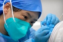 FILE - A medical worker gives a coronavirus shot to a patient in Beijing, Jan. 15, 2021. China is aiming to vaccinate 70-80% of its population by mid-2022, the head of the country's Center for Disease Control said March 13, 2021.