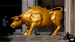 FILE - A homeless person sleeps next to the Golden Bull, a replica of Wall street Charging Bull symbolizing the financial market, outside the Brazilian B3 Stock Exchange in Sao Paulo, Brazil, Nov. 17, 2021. 