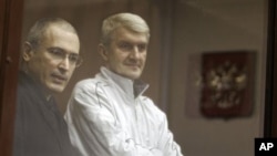 Former Yukos CEO Mikhail Khodorkovsky, left, and his co-defendant Platon Lebedev, right, stand behind a glass wall at a court in Moscow, Russia, (File)