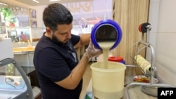 Samir Makari pours tahini sesame paste in a container as he prepares to make mufataka, a traditional Beiruti sweet, at his shop in the Lebanese capital on Aug. 29, 2024.