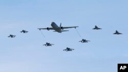 A Boeing KC-767 aerial refueling and strategic transport aircraft, center, flies along jet fighters during NATO Trident Juncture exercise 2015, in Trapani, Italy, Oct. 19, 2015. 