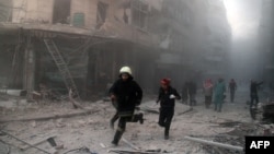 Emergency responders rush following a reported barrel bomb attack by government forces in the Al-Muasalat area in the northern Syrian city of Aleppo, Nov. 6, 2014. 