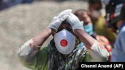 Reaksi seorang kerabat dari pasien COVID-19 yang meninggal di krematorium di Jammu, India, Minggu, 25 April 2021. (Foto: Channi Anand/AP)