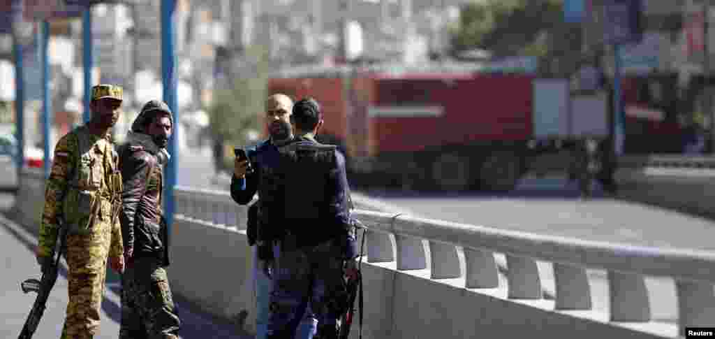 Security personnel gather as firefighting trucks drive to the Defense Ministry compound after an attack in Sana'a, Dec. 5, 2013. 