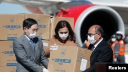 El embajador chino en Bolivia, Huang Yazhong, la canciller boliviana Karen Longaric y el ministro de sanidad Anibal Cruz recibiendo insumos médicos procedentes de China en el aeropuerto El Alto de La Paz (Bolivia). 