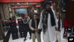 In this photo taken July 25, 2017, Mohammed Naseer, with black turban, holds his sons' hand when they enter a Pizza Restaurant in Kabul, Afghanistan. Mohammed Naseer spent several weeks arranging for his son, a nephew and several other children from his district to Quetta to study the Quran. (AP Photos/Massoud Hossaini) 