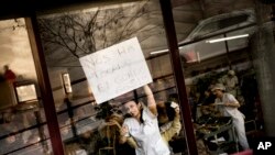 Una empleada de una residencia para ancianos, donde una mayoría del personal y residentes ganó la lotería de Navidad española, sostiene un cartel tras la ventana donde dice "Nos ha tocado el Gordo". 