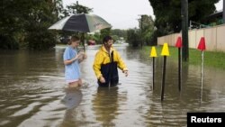 Resident Paul Shafer and his daughter Lily stand in floodwaters near star pickets that show where the storm water cover has been removed in Hermit Park, Townsville, northern Queensland, Australia, Feb. 2, 2019. 