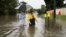 Resident Paul Shafer and his daughter Lily stand in floodwaters near star pickets that show where the storm water cover has been removed in Hermit Park, Townsville, northern Queensland, Australia, Feb. 2, 2019. 