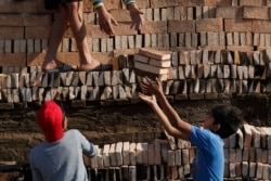 FILE - Children work with relatives to load a brick kiln for firing in Tobati, Paraguay, Sept. 4, 2020.