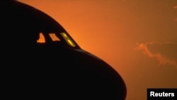 FILE - Airliner stands on a runway in the evening light.