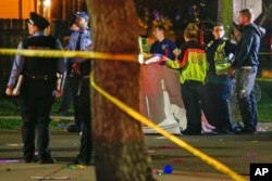 FILE - Emergency personnel work at the scene after a person was run over and killed by a float during The Mystic Krewe of Nyx Mardi Gras parade in New Orleans, Feb. 19, 2020.