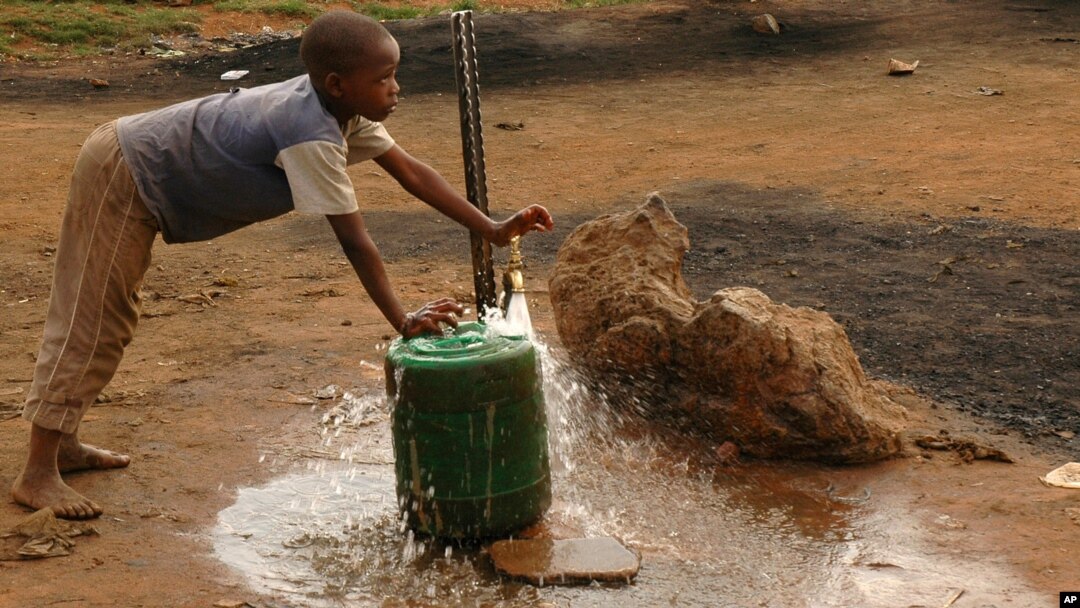 FILE - A child fills a container with water for domestic use in Delmas, east of Johannesburg, South Africa.