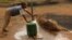 FILE - A child fills a container with water for domestic use in Delmas, east of Johannesburg, South Africa.