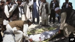 FILE - Relatives wrap the body of a civilian, who was killed during a clash of militants with policemen in Ghazni, southwest of Kabul, Afghanistan.