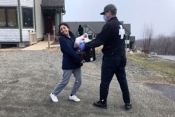 In this April 13, 2020 photo provided by Jay Peak Resort, Antonella Atto, left, from Peru, receives a week's supply of food from David Marchand, resort ski patrol director, in Jay, Vt.