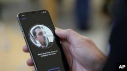 FILE - An Apple employee demonstrates the facial recognition feature of an iPhone in San Francisco. A new Apple tool called "neuralMatch" will detect known images of child sexual abuse on phones without decrypting people's messages.