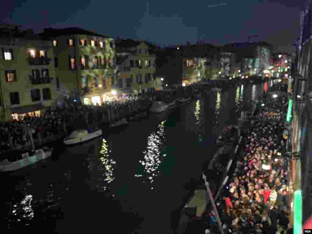 Crowds line up along the canal banks where Venice Carnival floats are expected, in Venice, Italy, Feb. 8, 2020.