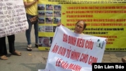 Bà Nguyễn Thị Việt, mẹ của tử tù Lê Văn Mạnh, cầm biểu ngữ kêu cứu cho con.