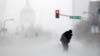 FILE - A person struggles to cross a street in blowing and falling snow in St. Louis, Missouri, January 2014.