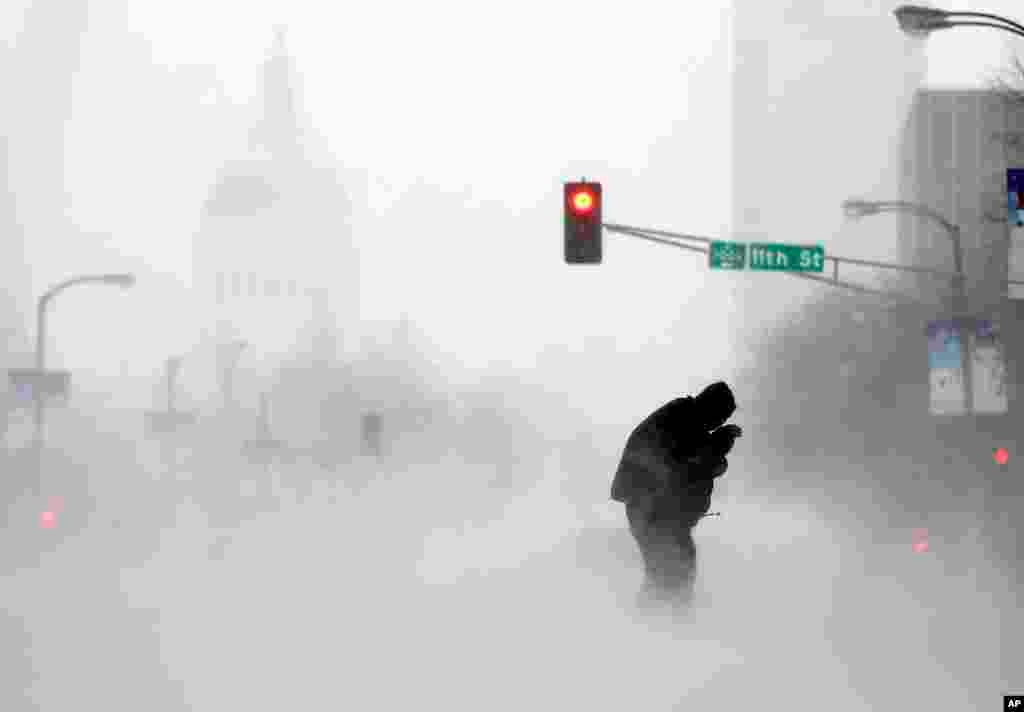 A person struggles to cross a street in blowing and falling snow in St. Louis, Missouri, USA.&nbsp;