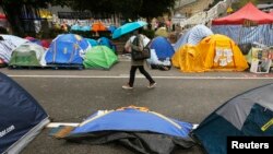 A passerby walks past a folded tent at a protest site blocking a main road outside the government headquarters at Admiralty in Hong Kong, December 4, 2014.