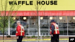 Emergency workers walk outside a Waffle House restaurant Sunday, April 22, 2018, in Nashville, Tenn. At least four people died after a gunman opened fire at the restaurant early Sunday.