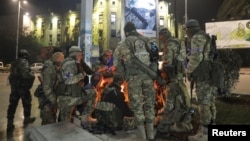 Los combatientes de la oposición siria se reúnen alrededor de una fogata para calentarse en la plaza Saadallah al-Jabiri, después de que los rebeldes opuestos al presidente Bashar al-Assad dijeran que habían llegado al corazón de Alepo.