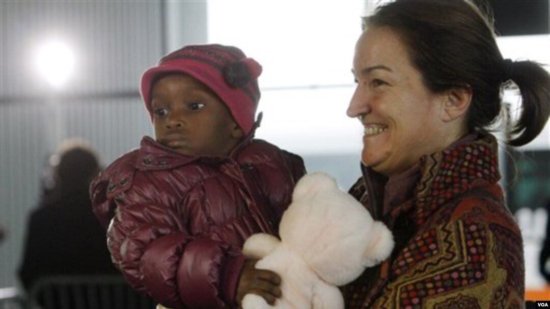 Seorang ibu warga Perancis menggendong anak adopsinya dari Haiti di bandara Roissy, Paris.