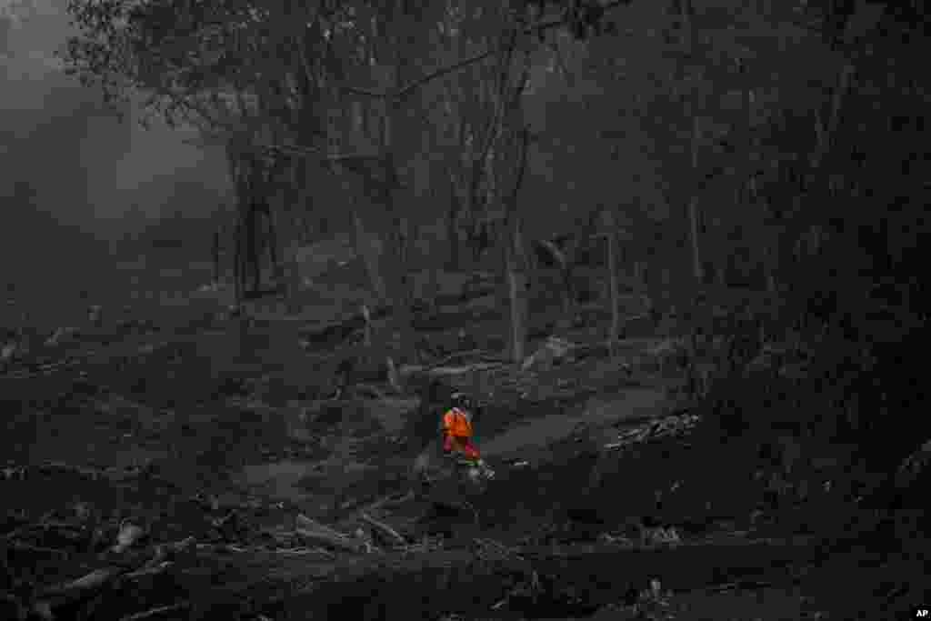 A rescuer looks for bodies in the area close to where the Las Lajas bridge used to be, before the recent explosion of the Volcan de Fuego, or Volcano of Fire, in El Rodeo, Guatemala.