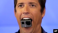 El CEO de GoPro, Nick Woodman, sostiene una cámara GoPro con su boca.