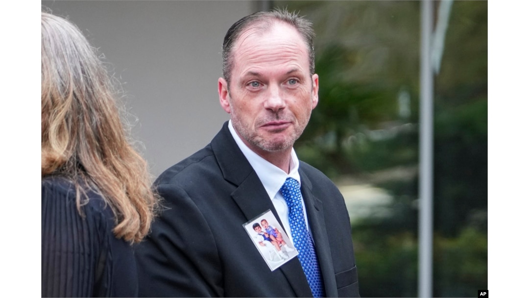 David Smith displays a photo of his two boys as he walks to a press conference after a parole hearing for convicted murderer Susan Smith in Columbia, South Carolina, Nov. 20, 2024.