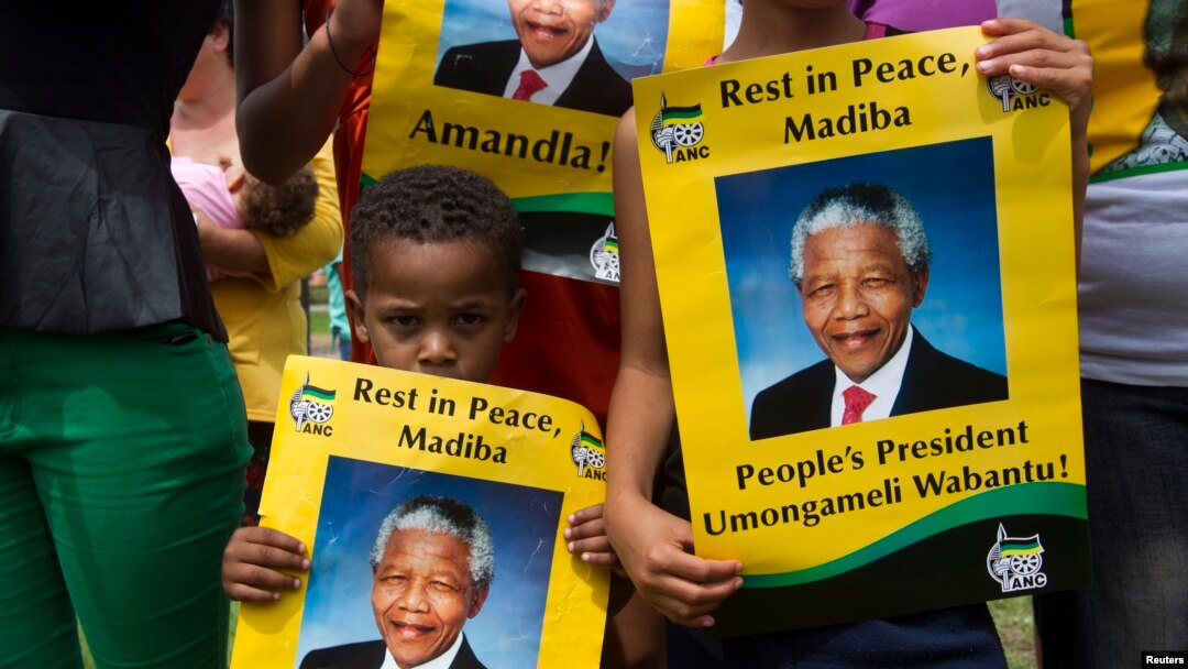 Seorang anak laki-laki memegang poster mantan presiden Afrika Selatan dekat Qunu, 13 Desember 2013. 
