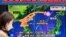 FILE - Seorang pejalan kaki berjalan melewati layar televisi yang menayangkan laporan berita tentang peluncuran rudal Korea Utara, di Tokyo, 18 Desember 2023.