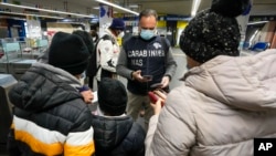 A Carabinieri policeman checks the green health pass of public transportation passengers in Rome, Italy, Dec. 6, 2021, on the first day a super green health pass went into effect. 