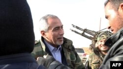 Omar al-Hassi, center, the head of Libya's self-declared Islamist-backed government greets soldiers during a visit to forces loyal to his unrecognized administration, west of Tripoli, Dec. 11, 2014.