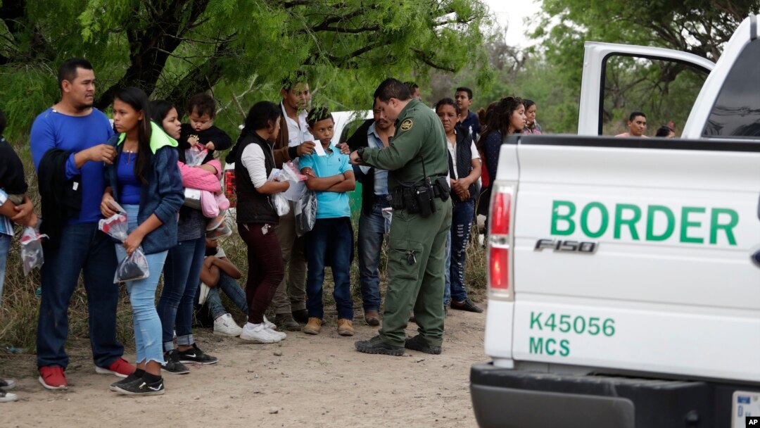 FILE - A U.S. Border Patrol agent checks the names and documents of families who crossed the nearby U.S.-Mexico border, near McAllen, Texas, March 14, 2019. 