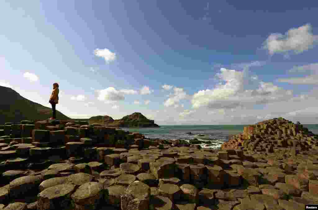 Seorang perempuan berdiri pada batu-batu karang &quot;Giant&#39;s Causeway&quot; di Irlandia Utara.