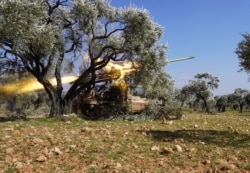 FILE - Members of Syria's opposition National Liberation Front fire a rocket near al-Nayrab, about 14 kilometers southeast of Idlib in northwestern Syria, amid clashes with government forces, Feb. 20, 2020.