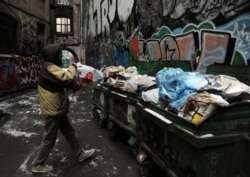 FILE - A man throws a garbage bag into a trash box in a courtyard in Russia's second city of St. Petersburg, Feb. 20, 2013.