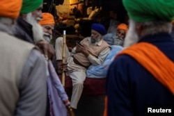 Farmers talk during a protest against the newly passed farm bills at Singhu border near Delhi, India, Dec. 3, 2020.