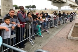 FILE - Asylum seekers in Tijuana, Mexico, listen to names being called from a waiting list to allow them an opportunity to make their case, at a border crossing in San Diego, California, Sept. 26, 2019.